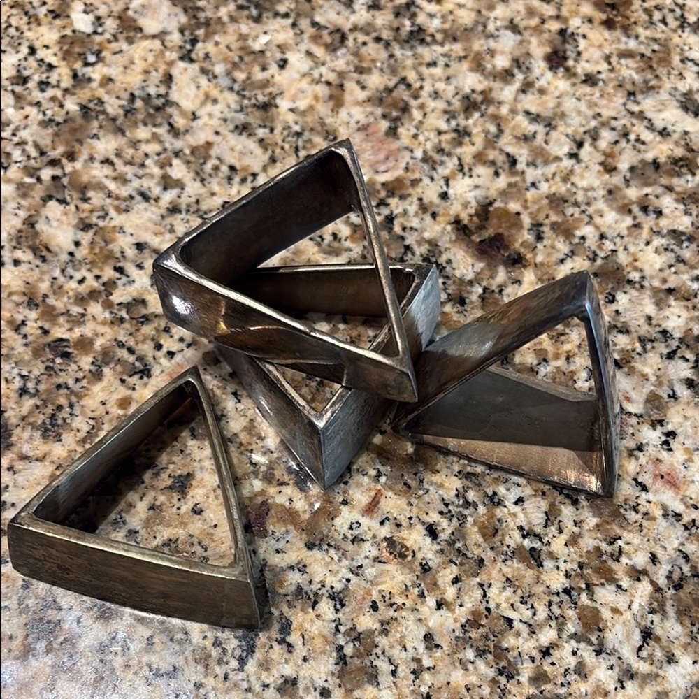 Set of four triangular silver plate napkin rings.   About 2” on each side